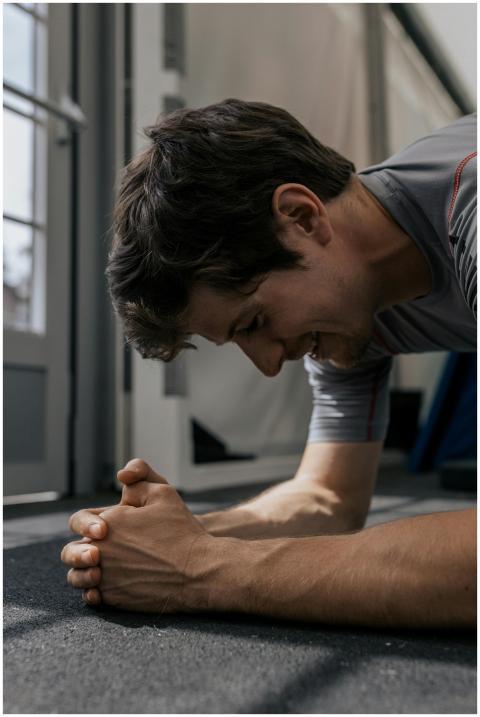 A man performs a plank exercise indoors, showcasin