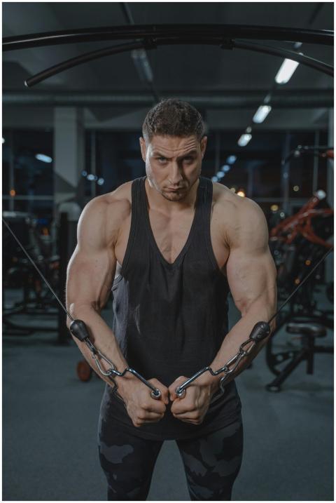 Strong man exercising on cable machine in gym show