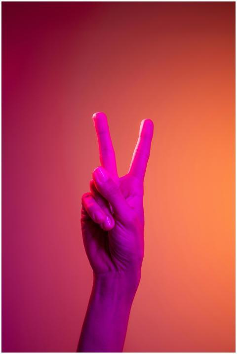 A vibrant neon-lit hand displaying the peace sign
