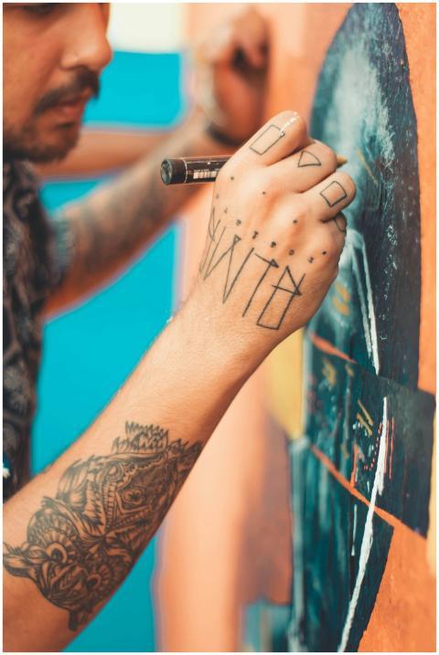 Tattooed artist creating a vibrant mural with intr
