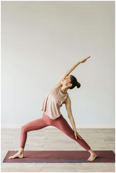 A young woman practices the Warrior yoga pose indo