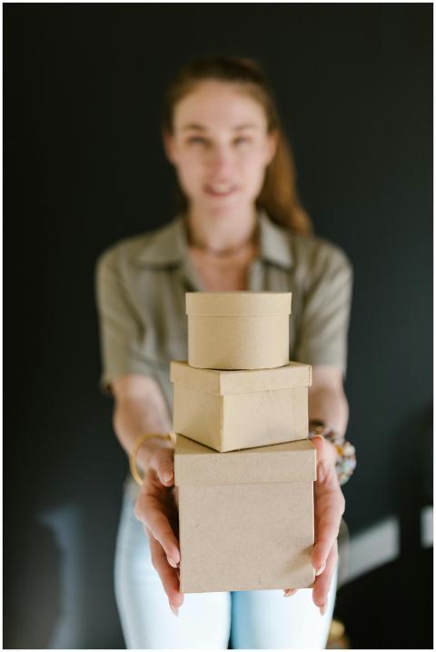 Blurred woman holding a stack of cardboard boxes,