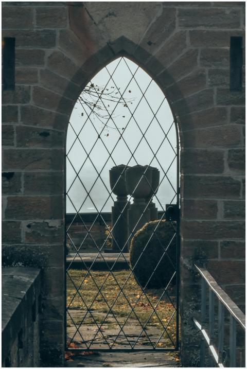A historic stone gate with metal latticework and a