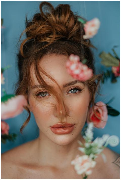 Artistic portrait of woman with flowers on blue ba