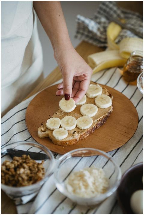 Hand placing banana slices on toasted bread. Perfe