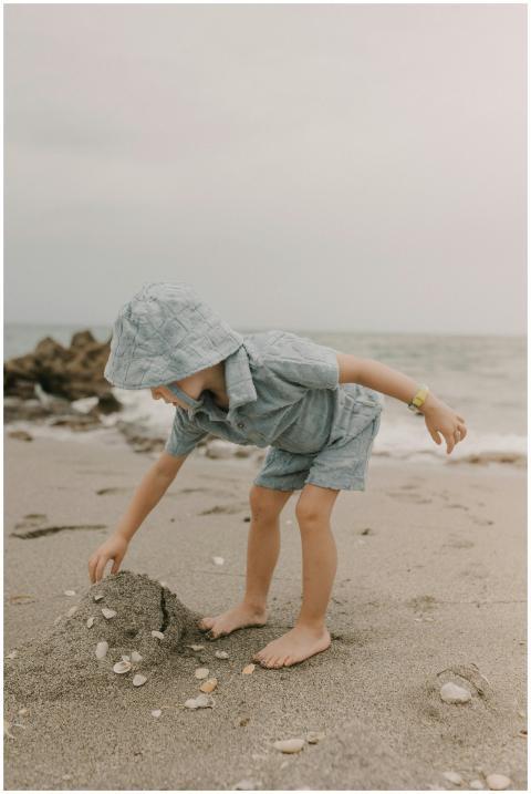 A young child in a hoodie plays with sand on Teque
