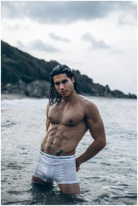 A muscular man posing confidently in ocean waters