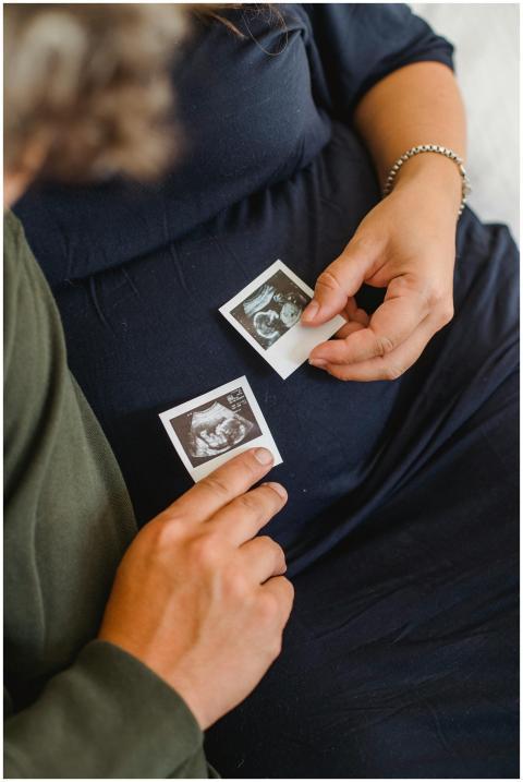 A pregnant couple holding ultrasound images, symbo