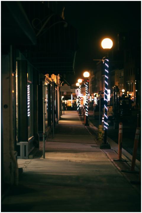 A dimly lit city sidewalk at night with decorative