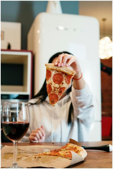 Woman enjoying a slice of pepperoni pizza and a gl