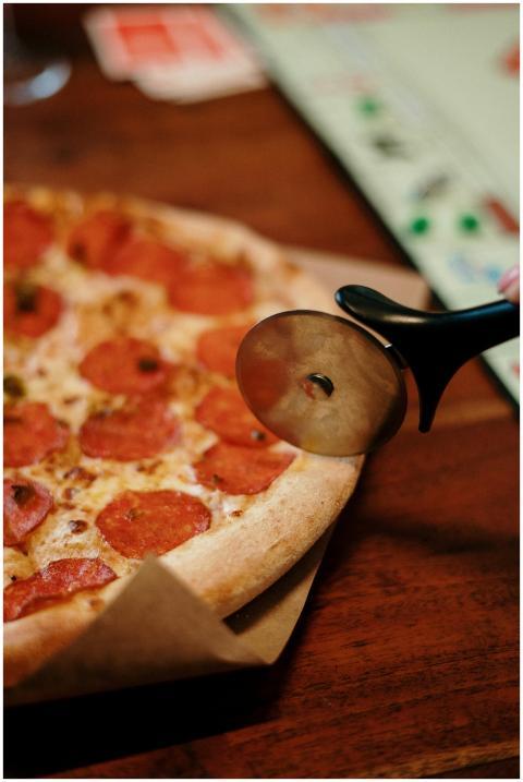 Close-up of a pepperoni pizza being sliced with a