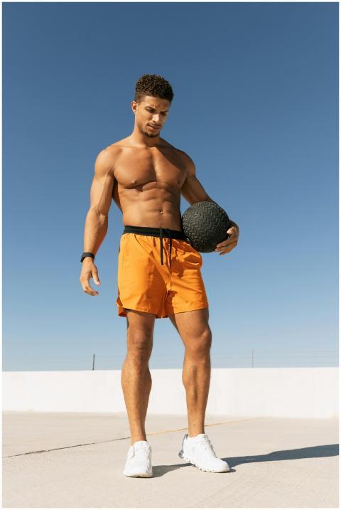 Fit young man in shorts exercising with a medicine