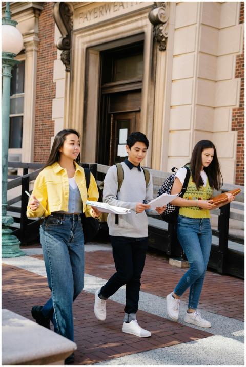 Three diverse students walking together outdoors o