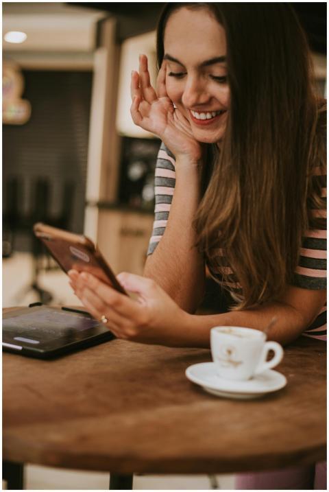 Smiling woman using her phone at a cozy coffee sho