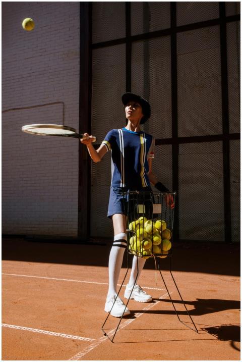 Female tennis player practicing on a clay court wi