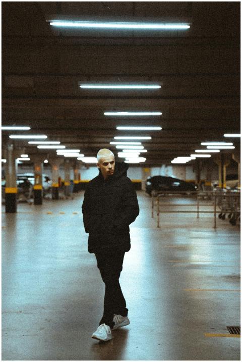 A fashionable man strolls through a dimly lit urba