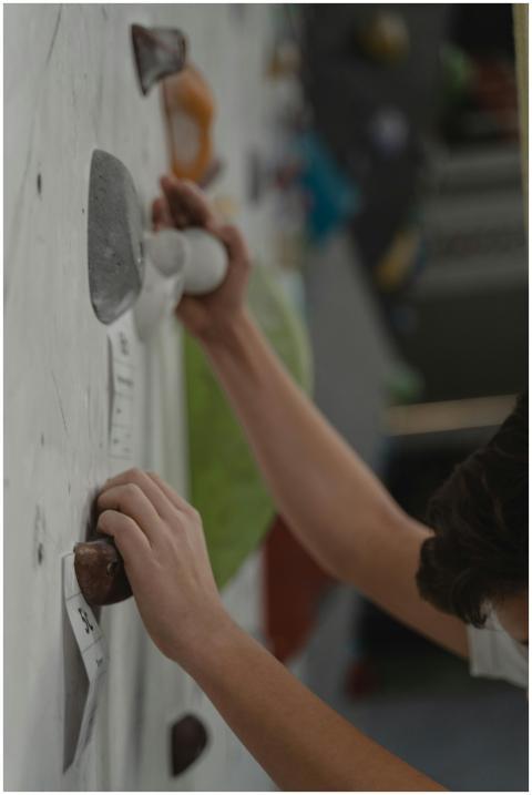 Close-up of hands gripping holds on an indoor clim