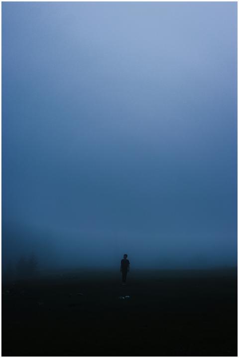 A solitary silhouette in dense fog creates a myste