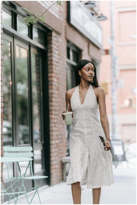 Stylish woman in polka dot dress walks outside a c