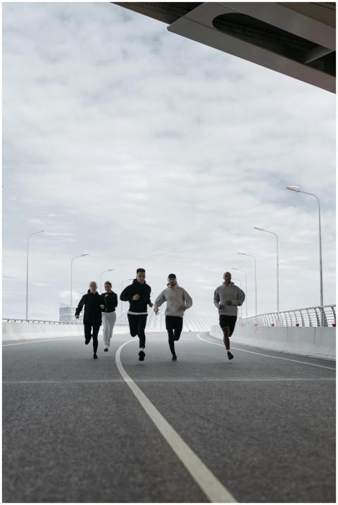 A diverse group of friends jogging on a bridge und