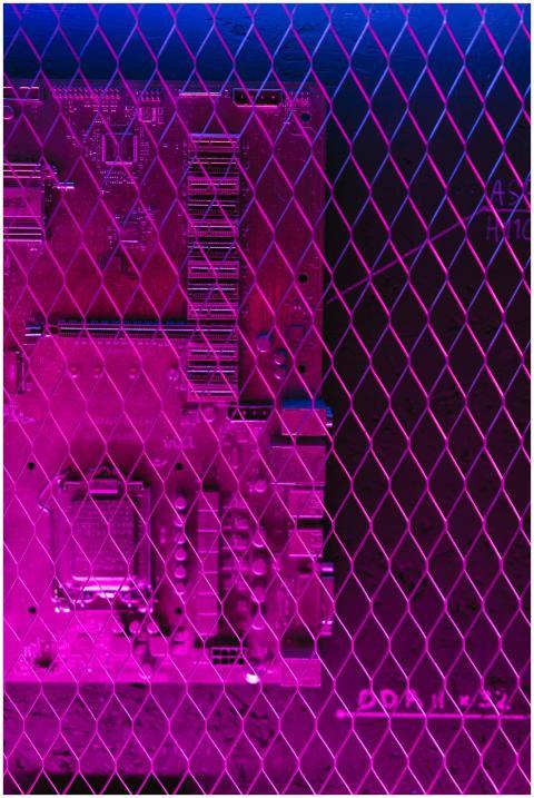 Colorful neon circuit board behind mesh, creating