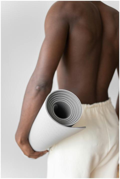 Shirtless man holding a gray yoga mat, promoting a