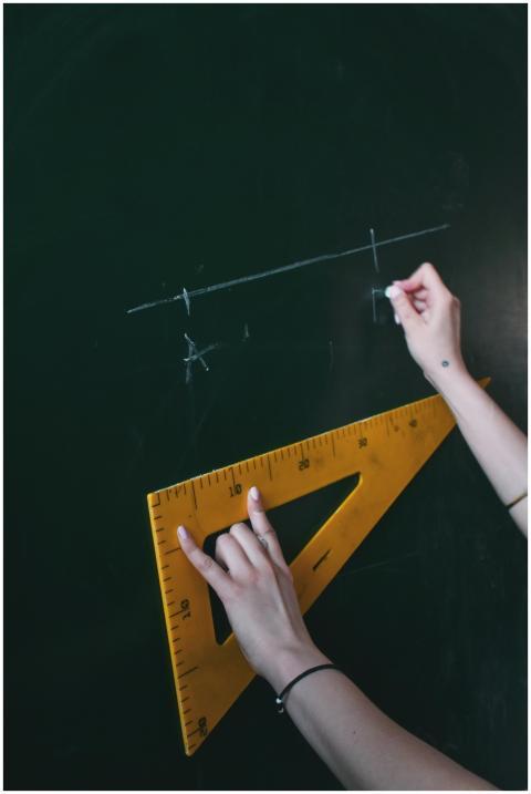 Two hands drawing a line with chalk on a blackboar