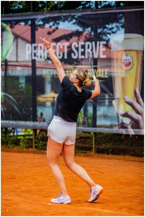 A female athlete in sportswear serves a tennis bal