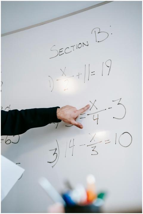 Close-up of an instructor's hand solving math equa