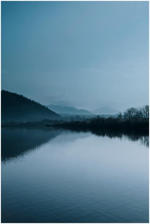 Peaceful misty morning view over a calm lake and h