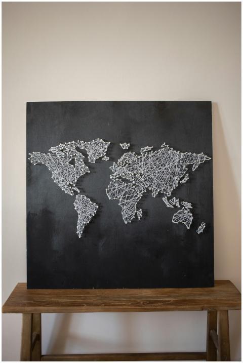 Creative world map string art displayed on a woode