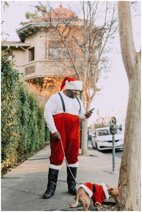 African American man dressed as Santa walking a do