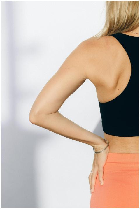 Close-up of a woman in sportswear, hand on waist,