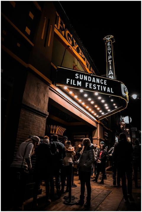 Crowd gathers under the illuminated marquee of the