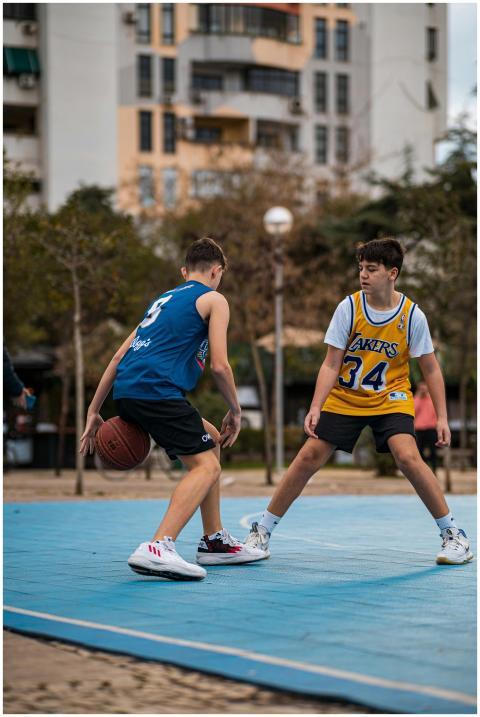 Two teenagers in sports jerseys playing basketball