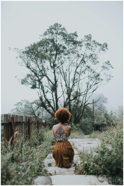 A woman sits alone on a misty path surrounded by l
