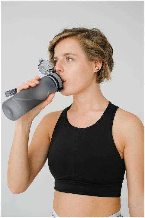 Young woman in athletic wear sipping water from a