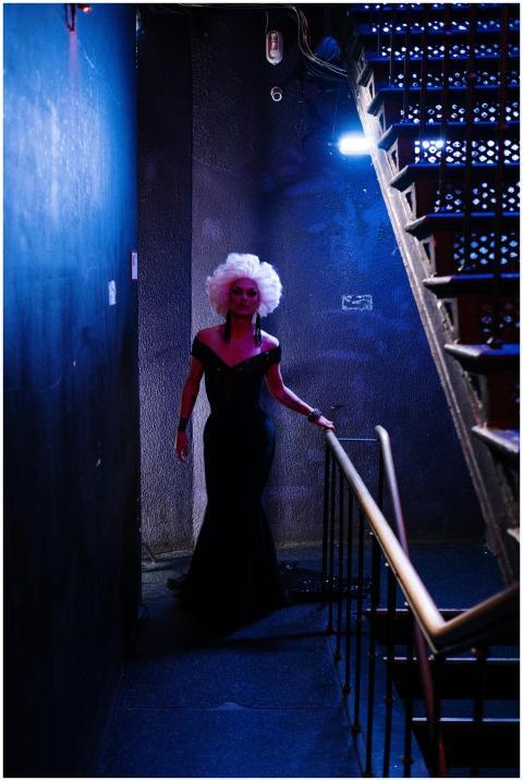 A glamorous drag queen in a black dress navigating