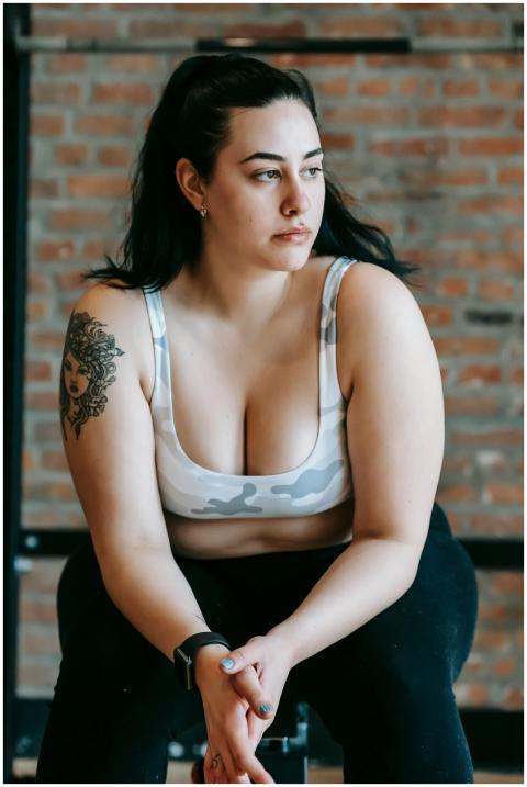 Thoughtful plus size woman in sportswear sitting a