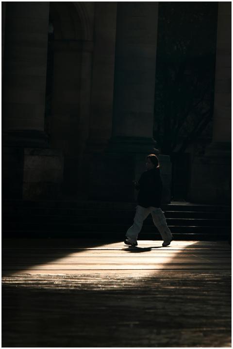 A person walks through a shadowy urban setting wit
