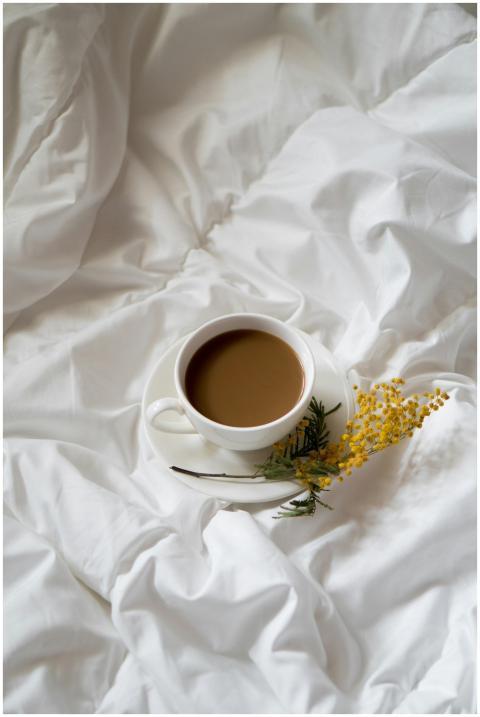 A cup of coffee on white sheets adorned with yello