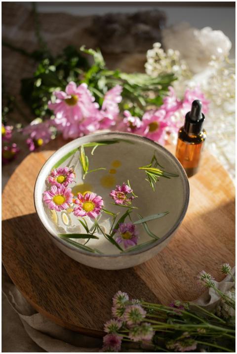A bowl of water with floating flowers and essentia