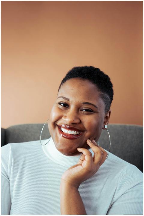 Smiling woman in white turtleneck posing indoors w