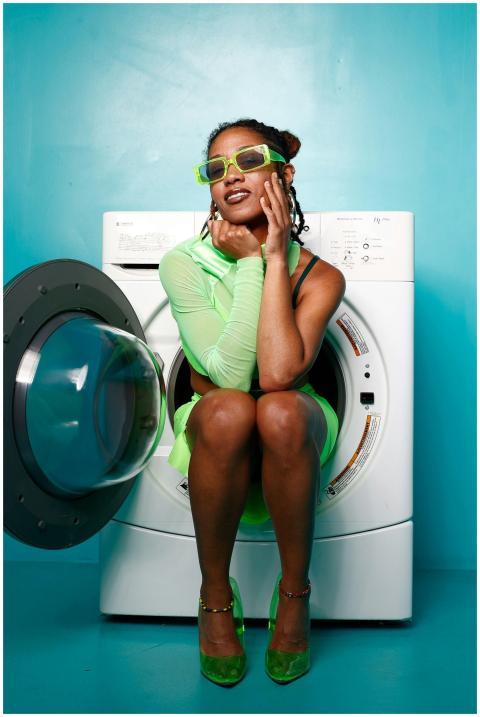 A fashionable woman in a green outfit poses creati