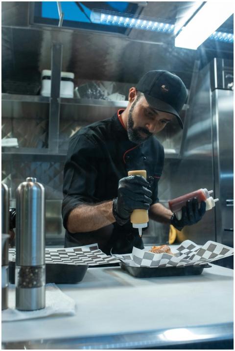 A chef skillfully adding condiments to a dish in a