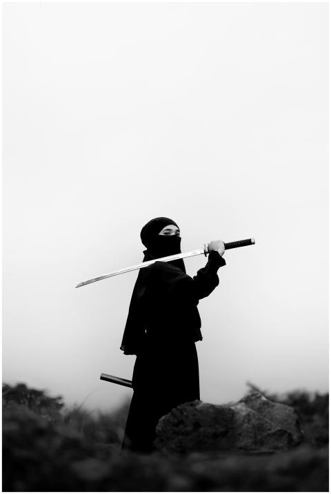 A ninja in black attire holding a katana sword in