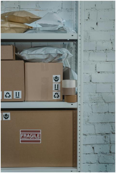 A warehouse shelf with labeled cardboard boxes and
