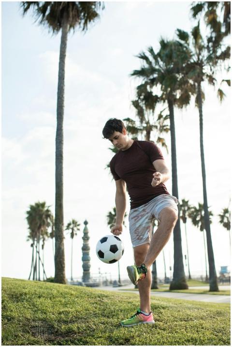 Caucasian man plays soccer in a sunny park with pa