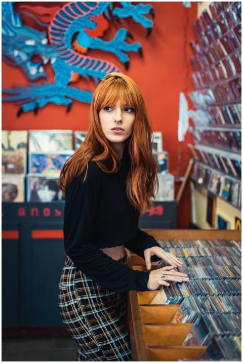 A woman with red hair explores a vibrant music sto