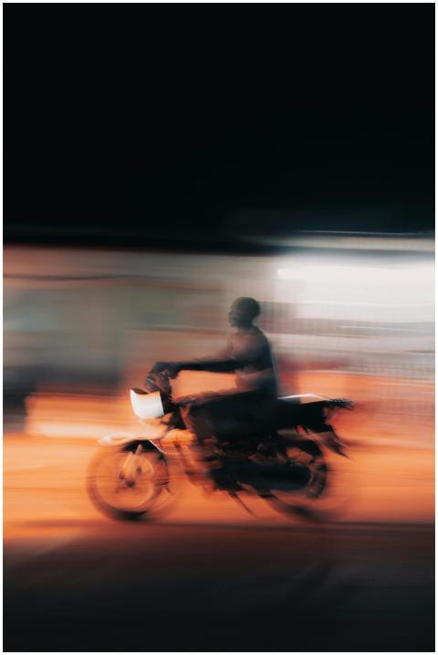 A motorcycle with a rider speeding at night, captu